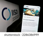 Small photo of Stuttgart, Germany - 04-01-2023: Person holding smartphone with webpage of think tank IISD institute on screen in front of logo. Focus on center of phone display. Unmodified photo.