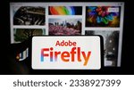Small photo of Stuttgart, Germany - 07-15-2023: Person holding cellphone with logo of generative AI product Adobe Firefly on screen in front of business webpage. Focus on phone display. Unmodified photo.