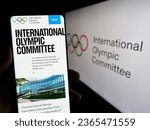 Small photo of Stuttgart, Germany - 06-24-2023: Person holding smartphone with website of the International Olympic Committee (IOC) on screen in front of logo. Focus on center of phone display. Unmodified photo.