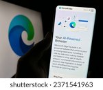 Small photo of Stuttgart, Germany - 09-21-2023: Person holding cellphone with webpage of web browser Microsoft Edge on screen in front of product logo. Focus on center of phone display. Unmodified photo.