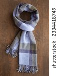 Small photo of Scarf of purple, olive and lilac color on the wooden table, vertical format. Concept of neckwear, neckcloth, warm accessories
