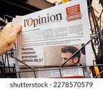 Small photo of Paris, France - Mar 20, 2023: l'opinion headline title in male hand at newspaper press kiosk - Macron, how to govern after 49.3
