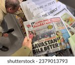 Small photo of Frankfurt, Germany - Feb 24, 2023: A man with glasses is purchasing a copy of the Hurriyet newspaper at a store. The main headline, related to a devastating earthquake, translates to Even Worse Than
