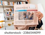 Small photo of Paris, France - Oct 3, 2023: Woman reading latest Financial times with headlinne about gaza alarm and chevron doubles down on fossil fule wager with 53bn swoop for hess
