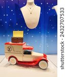 Small photo of Strasbourg, France - Dec 25, 2023: A vintage car, dusted with snow, bears a message of Happy Holidays in the showcase of the Louis Vuitton store, with elegant necklaces and jewelry adorning the