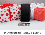 Smartphone with a bank card and Christmas gifts on the table. Online shopping festive internet concept.