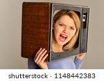 Small photo of television set. television set on head of angry woman. woman hold television set in hands. television set and new technology. bang