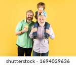 Male Multi Generation Portrait. Happy three age multi generation. Men family grandfather father and son having fun on yellow studio background isolated