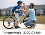 Small photo of Father and son riding bike in park. Child in safety helmet with father riding bike in summer day. Father teaching son riding bike. Father helping son to wear a cycling helmet. Child in safety helmet.