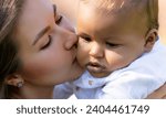 Small photo of Close up portrait of mother kissing multiracial baby. Mom kiss Biracial child. Closeup face of Mother with Biracial baby kissing outdoor. Tender moms kiss. Biracial or multiracial baby and mom kissed.