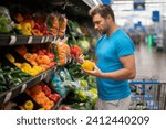 Small photo of Handsome man with shopping basket with grocery. Man buying groceries in supermarket. Male model in shop. Concept of shopping at supermarket. Shopping with grocery cart at grocery store.