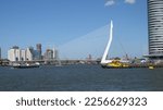 Small photo of Rotterdam, The Netherlands - August 21 2020: View on the abridge in the city of Rotterdam, The Netherlands. Some boats sailing in the water. A blue sky in the background.