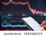 Small photo of Investor analyzing stock market investments on a smartphone. Person trading stocks on a smartphone. Falling share prices at the stock exchange. Stock market crash. Trader at the stock exchange.
