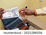 An african hand receiving Nigerian Naira notes, cash or currency with a laptop in the background