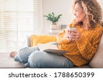 Woman have relax at home with cup of tea and book - reading activity for adult beautiful female people - enjoying quiet lifestyle indoor and long blonde curly hair - happy adult female indoor - people