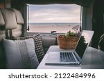 Remote onilne work and smart working travel concept with laptop computer inside a van camper interior with beach view. Freedom from office modern lifestyle for alternative life and people