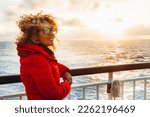 Cruise ship vacation woman enjoying sunset on travel at sea. Traveler happy woman in red jacket looking at ocean relaxing on luxury cruise liner boat. People and ferry boat transport. Travel activity