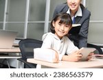 Small photo of A cram school instructor teaches an elementary school girl how to use a tablet in the classroom.