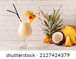 Small photo of Traditional caribbean cocktail pina colada in a glass, garnished with a slice of pineapple.