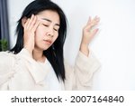 Small photo of Asian woman having problem with Meniere's disease, fainting or dizziness hand holding her head leaning against the wall