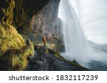 Adventurous man standing under the waterfall, The Seljalandsfoss waterfall in the southern part of Iceland