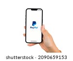 Small photo of Female hand holding a smartphone iPhone 13 Pro with PayPal app on the screen. White background. Rio de Janeiro, RJ, Brazil. November 2021.
