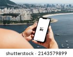 Small photo of Girl holding smartphone with Nike Training Club NTC app on screen. City and bay with some boats in the background. Rio de Janeiro, RJ, Brazil. March 2022.