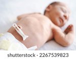 Small photo of Defocused caucasian hairy brunet cute newborn baby few days old,sleeping,lying on bed on back,umbilical cord remnant.Close up of belly button.Few days old child wearing diaper.