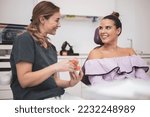Small photo of The woman dentist shows dentures with a bracket in her hands to the patient. False teeth in the hands of the follow-up doctor. prosthetic dentistry. Fake teeth.
