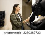 Small photo of A pregnant Caucasian woman at a children's supply store. The adult girl is choosing a child restraint chair. Concept of choice of child restraint chairs or seats.