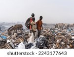 Small photo of Three African street kids standing in a steaming dump amid donkeys looking for recyclable items to sell