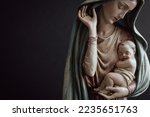 Virgin Mary and infant Jesus in her arms on a black background with copy space 