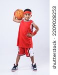 Small photo of Full-length profile studio shot of an Asian boy in a red jersey holding a basketball