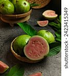 Small photo of Several guavas were placed on a bamboo plate, some were whole and some had been cut, there were also leaves scattered on the table