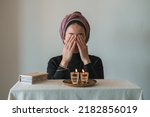 Small photo of Jewish woman prays over lit Shabbat candles, covering her face with her hands. Nearby lies a religious prayer book. Jewish religious traditions (71)