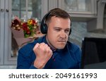Small photo of Angry man with headphones clenched his fist, looking at laptop screen, writes offensive comments to haters, spreads fake rumors, feeds trolls online. Concept hate, trolling, anger on Internet forum