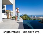 Couple standing and hugging on the balcony next to a swimming pool with the sea in the background