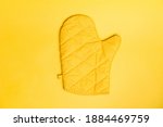 Top view of yellow oven gloves on yellow color background. Mockup for food banner and kitchen protection equipment.