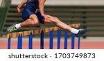 Small photo of Athlete running a hurdle race in a stadium, runner jumping over an hurdle during track and field event