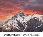Small photo of Scenery with a view of a mountain snow-covered peak. Sunset or sunrise, pink and red epic sky. Travel, tourism to the Caucasus Mountains, Dombay. The concept of wildlife without a trace of humans.