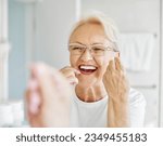Small photo of Portrait of an elderly senior woman is cleaning brushing his teeth using dental floss in front of mirror in bathroom. Dental hygiene, vitality and beauty concepts