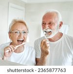 Small photo of Portrait of an elderly senior couple cleaning brushing their teeth in front of mirror in bathroom. Dental hygiene, vitality, love and beauty concepts