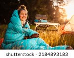 Small photo of Woman relaxing and lie in a sleeping bag in the tent. Sunset camping in forest. Mountains landscape travel lifestyle camping. Summer travel outdoor adventure