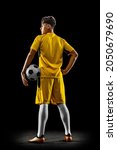 Small photo of Back view full-length portrait of young handsome football player in yellow uniform isolated over black background. Concept of action, team sport game, energy, vitality. Copy space for ad.
