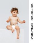 Small photo of Smiling happy child. Portrait of little toddler boy, baby in diaper joyfully sitting and laughing isolated on white studio background. Concept of childhood, motherhood, life, birth. Copy space for ad