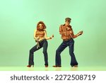Feeling rhythm. Couple happy people, man and woman in retro style clothes dancing disco dance over green background. Concept of 1970s, 1980s fashion, music, hippie lifestyle