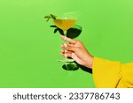 Alcoholic drink. Hand holding high glass with bronx cocktail over bright green background. Concept of alcohol, drinks, pop art, party and relax. Copy space for ad