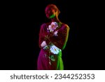 Half-length image of young relaxing woman posing in neon light isolated on dark mode background. Flower reflection. Copy space for ad. Concept of emotions, facial expression, youth, aspiration.