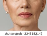Small photo of Cropped portrait of elderly woman with wonderful skin, full lips over grey studio background. Mimic wrinkles. Concept of fashion, beauty, spa, cosmetology, skincare.
