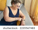 Small photo of Elderly woman asking for help by pressing the telecare button on her wristband. Emergency Button Concept. Medical alert concept.
